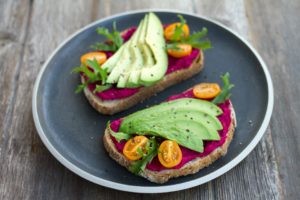 A plate of avocado toast garnished with cherry tomatoes and herbs