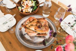 Dinner table set with a salad and roast chicken served on a platter