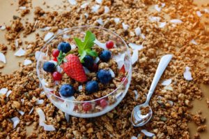 Bowl of Greek yogurt garnished with granola, strawberries and blueberries