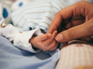 New mother holding baby's tiny hand in the hospital