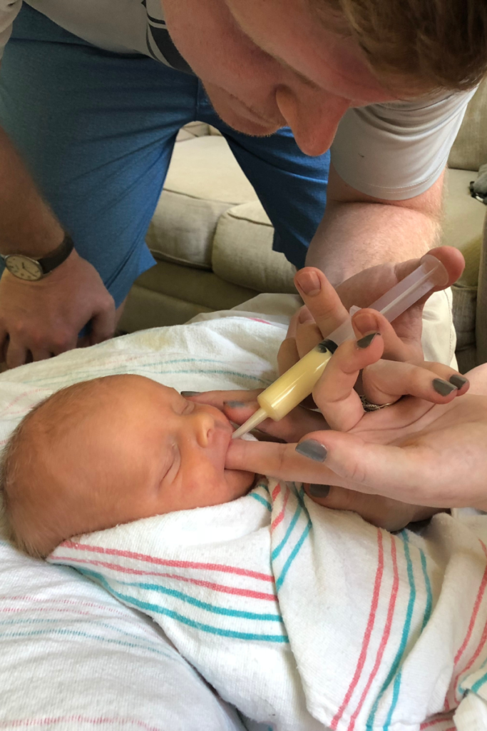 Father Giving His Daughter Milk With a Syringe