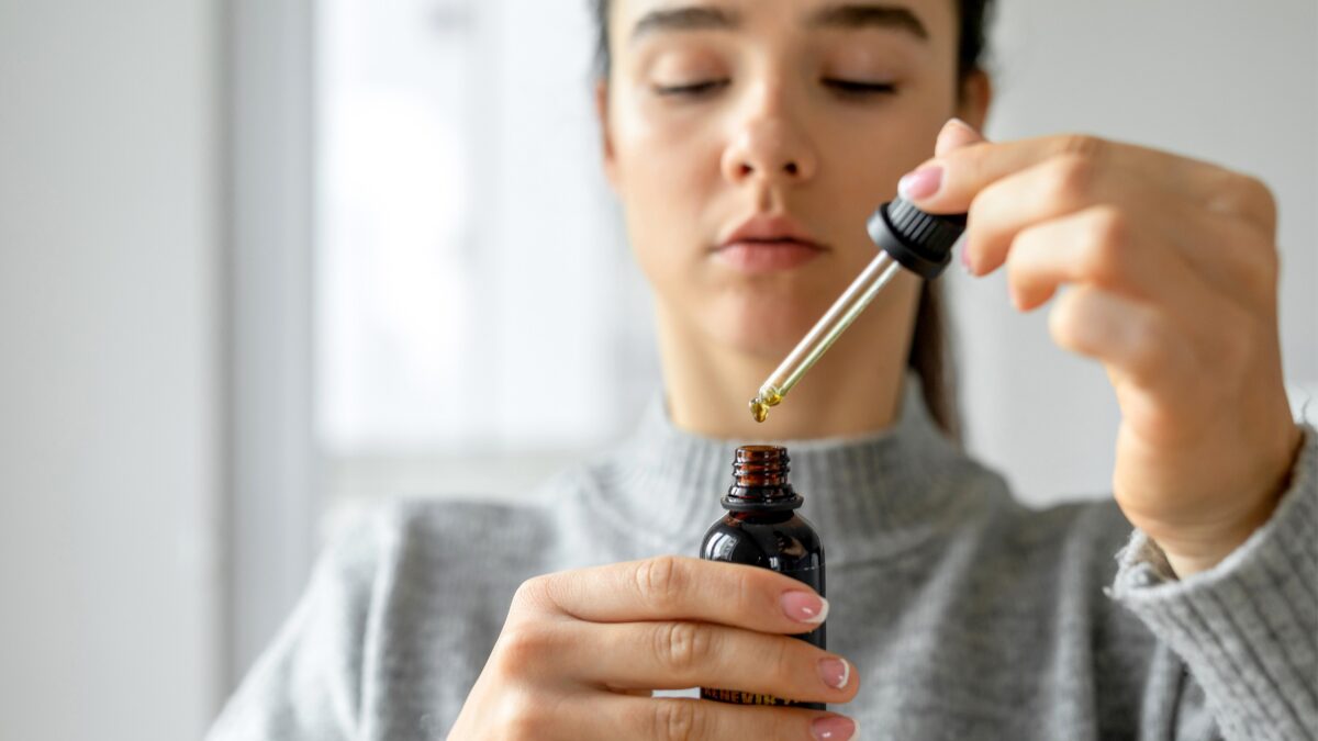 woman taking CBD out of tincture